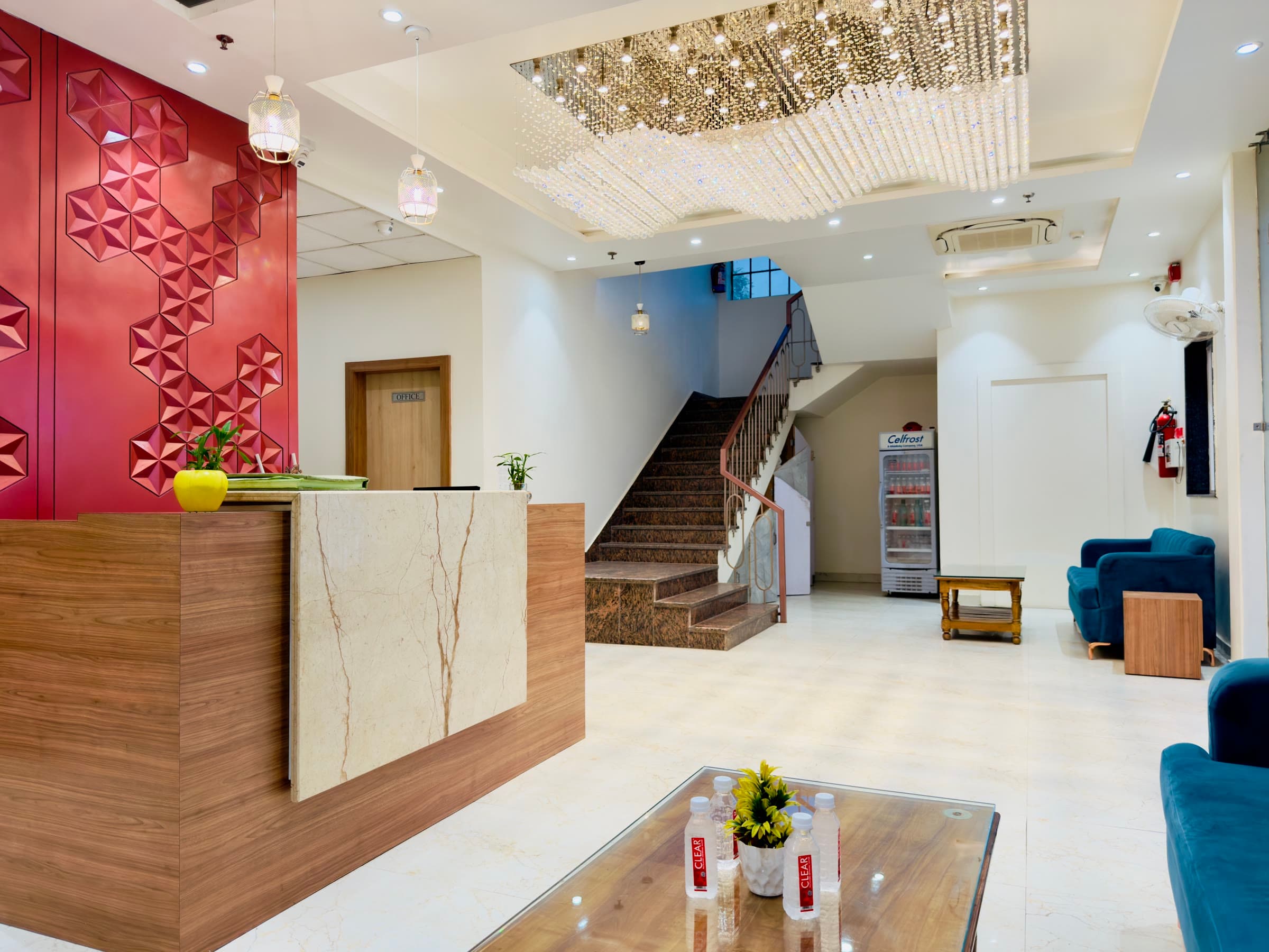 The marble lobby of Hotel Satsang Grand, with its crimson feature wall and crystal chandelier